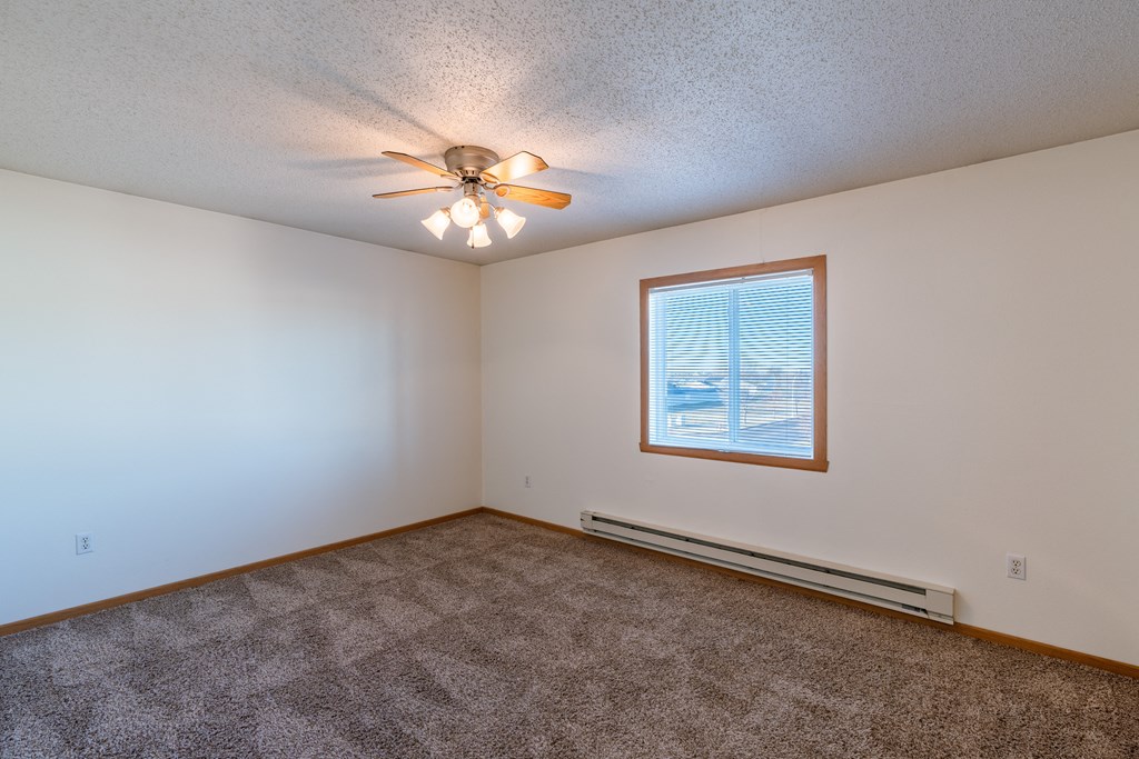 a bedroom  with a window and ceiling fan.  Fargo, ND Sunwood Apartments  | Living and kitchen Fargo, ND Sunwood Apartments