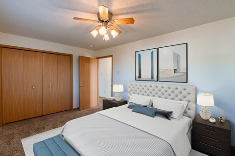 a bedroom with a large bed and a ceiling fan. Fargo, ND Sunwood Apartments