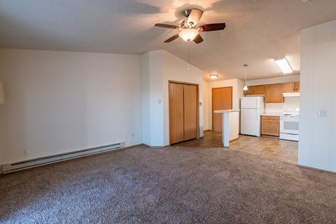 a living room with a kitchen and closet in the background. Fargo, ND Sunwood Apartments