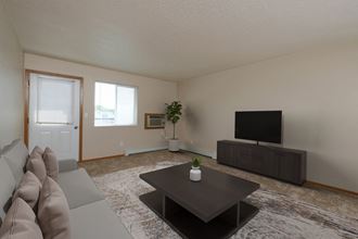 Fargo, ND Thunder Creek Apartments. The room is beautifully furnished with cozy seating, a coffee table, and stylish decor, creating a welcoming and relaxing environment. A small window brings natural light into the room. - Photo Gallery 2
