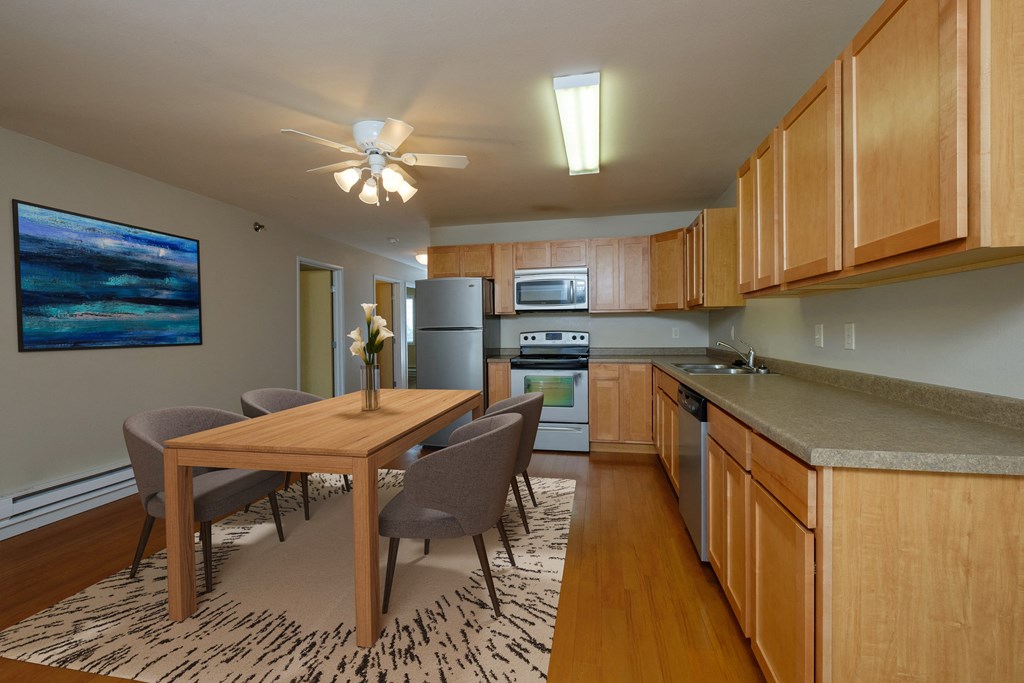 Fargo, ND Thunder Creek Apartments. A modern and well-equipped kitchen and dining area.. The space features sleek appliances, a spacious dining table, and tasteful decor, creating an inviting and functional environment for cooking and dining