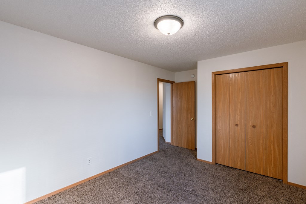 a bedroom with a closet door. Fargo, ND Thunder Creek Apartments