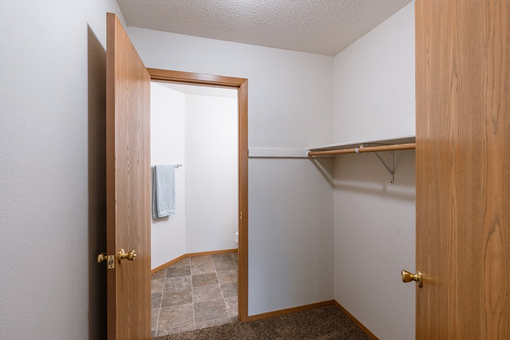 a bathroom with an open door and a closet. Fargo, ND Thunder Creek Apartments
