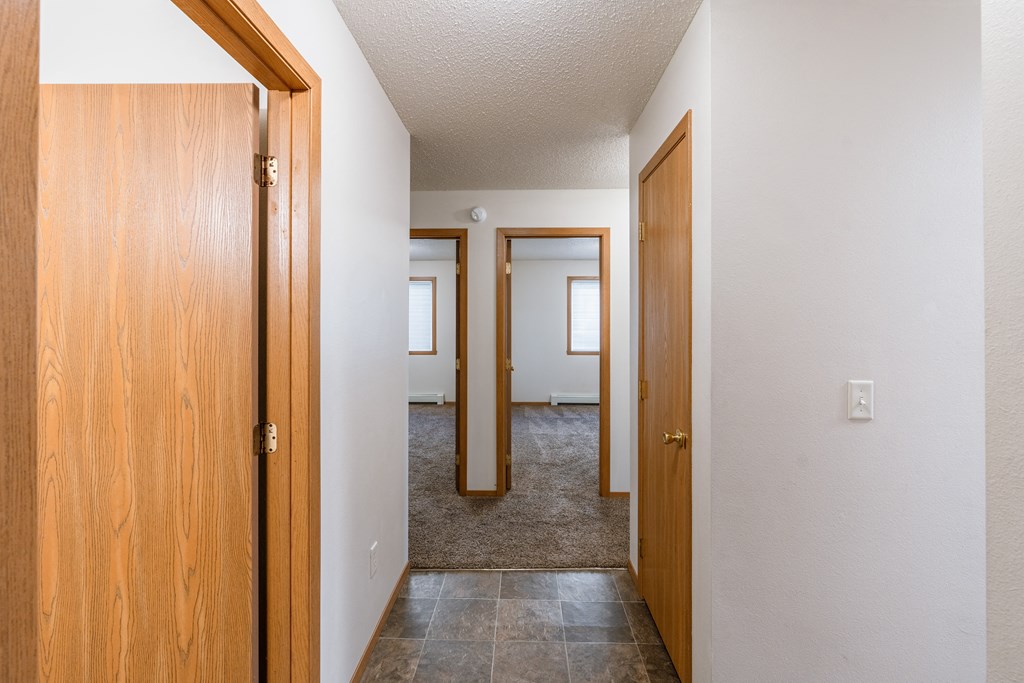 the view of a hallway with two doors and a door to a bedroom. Fargo, ND Thunder Creek Apartments