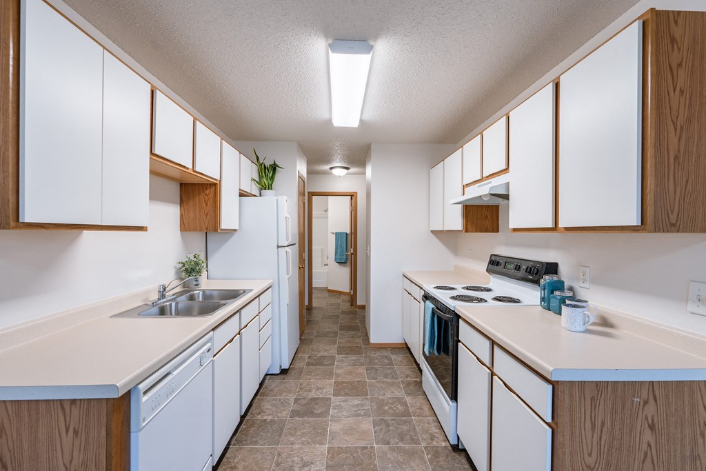 a kitchen with white cabinets and white appliances and a white counter top. Fargo, ND Thunder Creek Apartments
