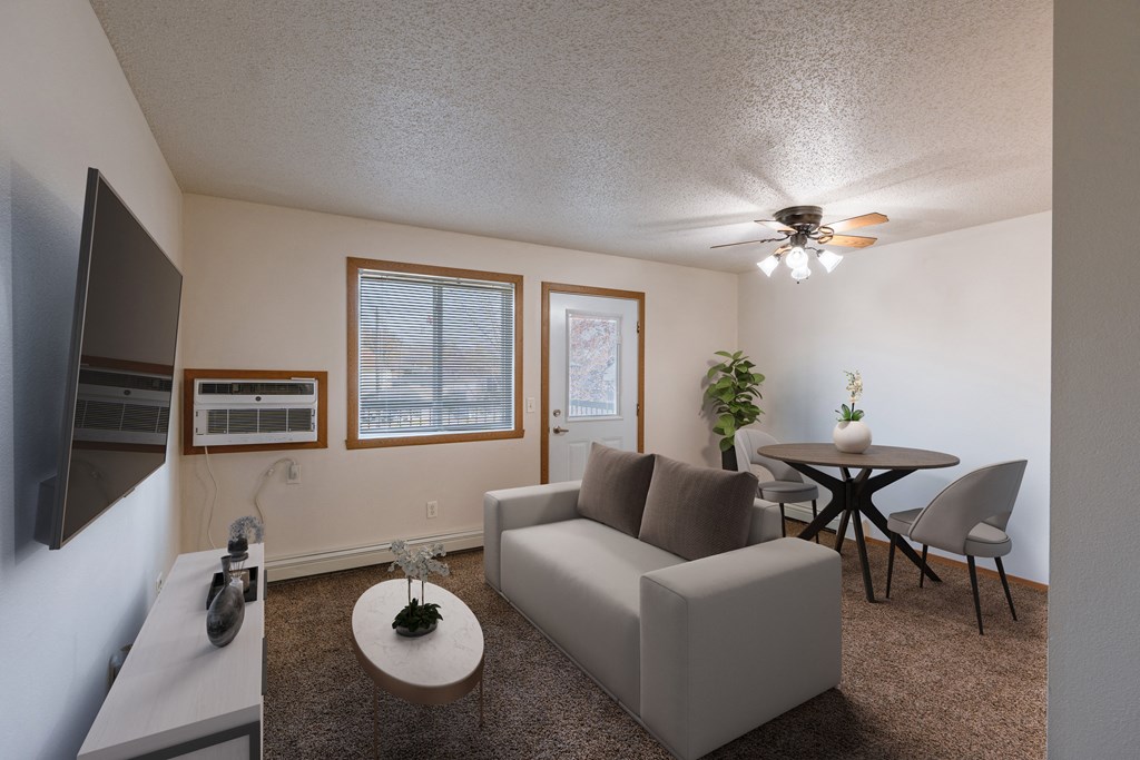a living room with a couch and a table and a ceiling fan. Fargo, ND Thunder Creek Apartments