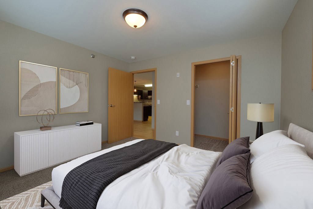 a bedroom with a bed and a door to a bathroom. Fargo, ND Urban Plains Apartments