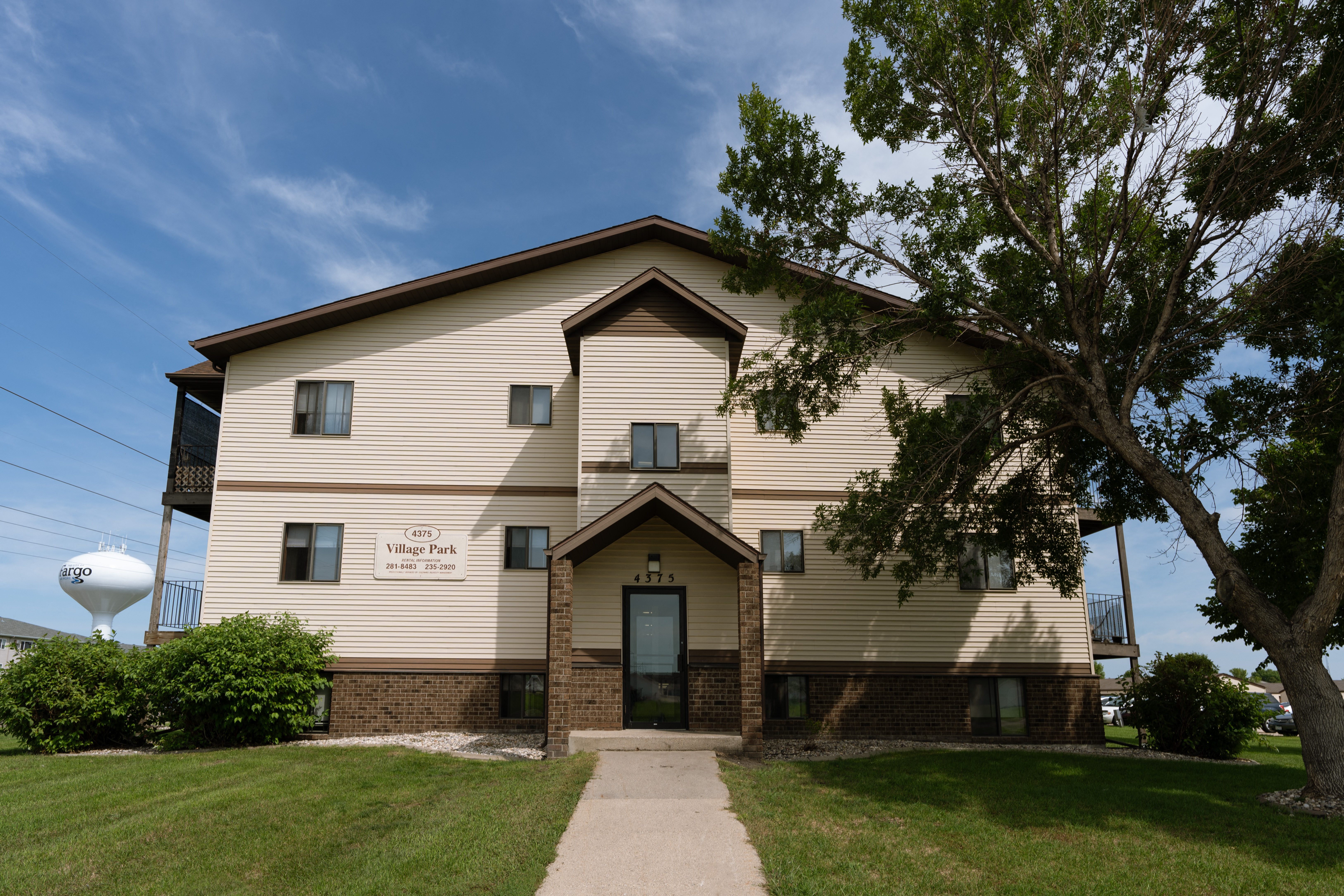 Fargo, ND Village Park Apartments. An image of the front of a large building with a water tower in the background