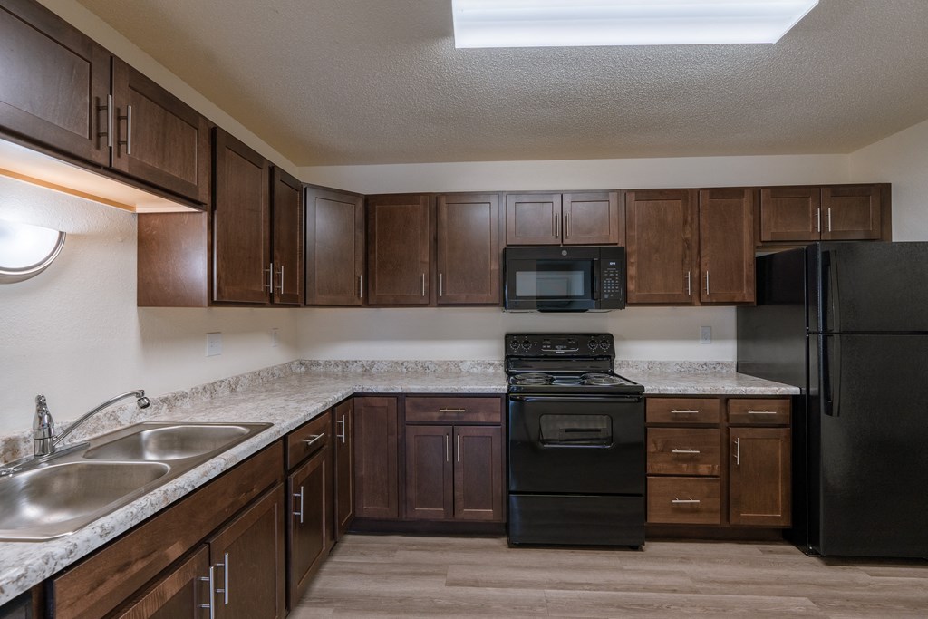 a kitchen with black appliances and white countertops. Fargo, ND Village West Apartments