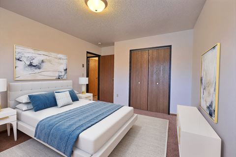 a bedroom with a bed and a chair in a room. Fargo, ND Village West Apartments