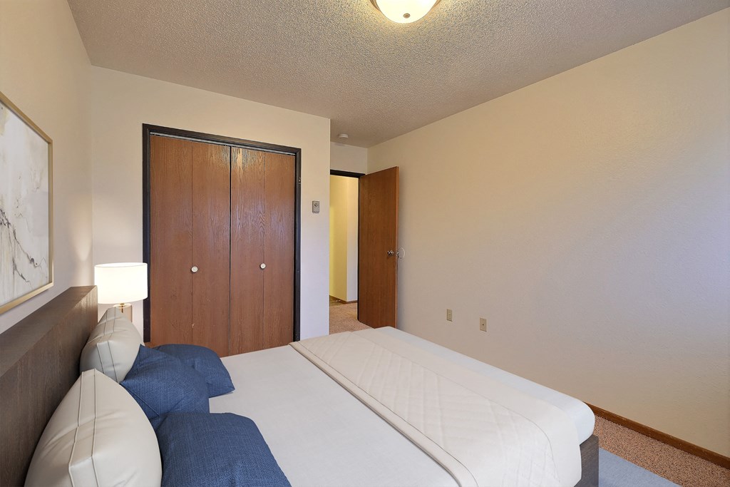 a bedroom with a bed and a wardrobe. Fargo, ND Village West Apartments