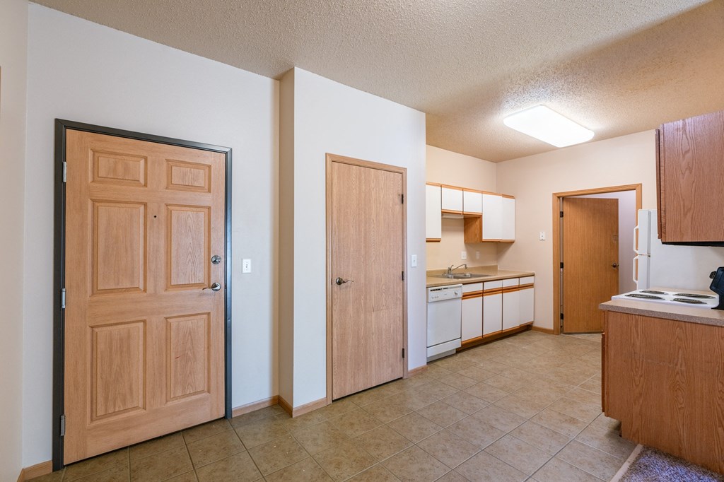 the view of a kitchen and a living room with wooden doors. Fargo, ND West Lake Apartments