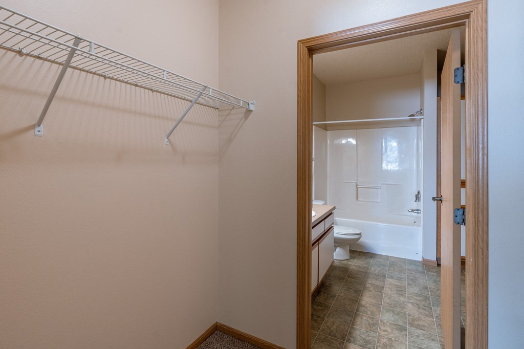 a bathroom with a shower and a toilet and a closet. Fargo, ND West Lake Apartments