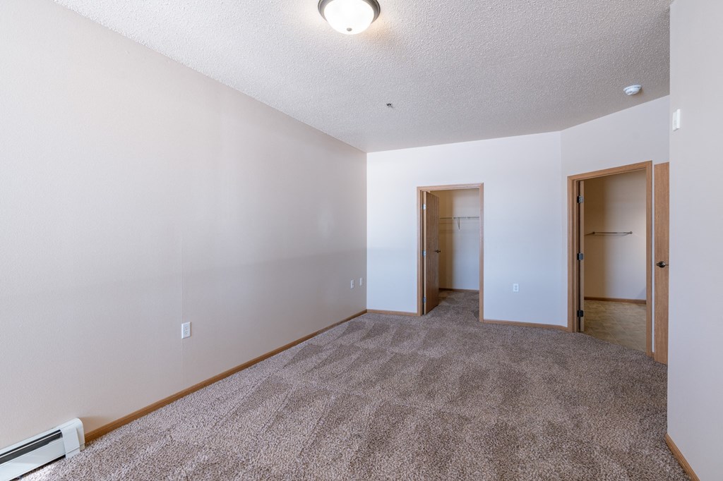 a bedroom with brown walls and carpet. Fargo, ND West Lake Apartments