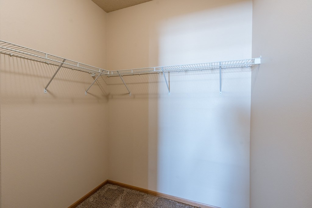 a walk in closet with a white curtain and a wire rack on the wall. Fargo, ND West Lake Apartments