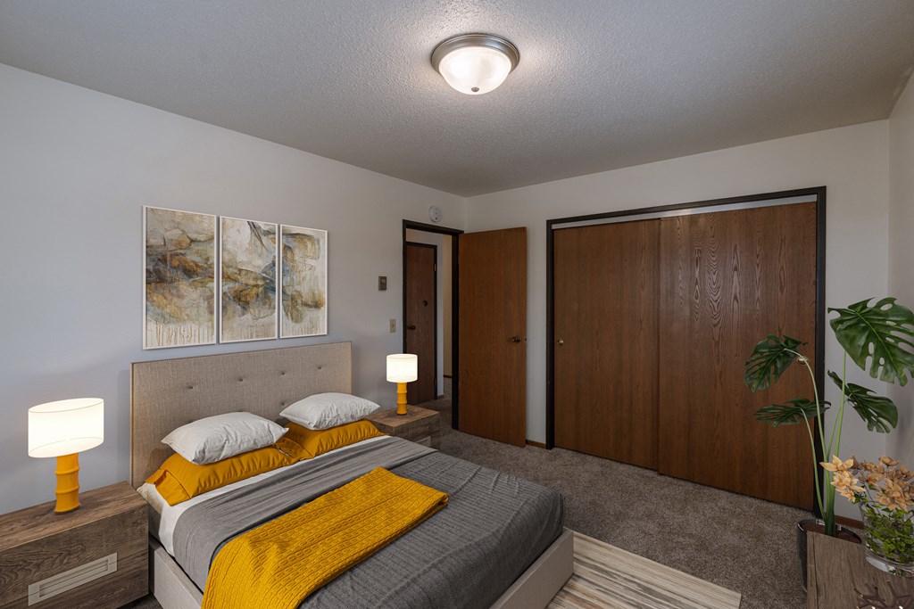 a bedroom with a bed and a closet. Fargo, ND West Oak Apartments