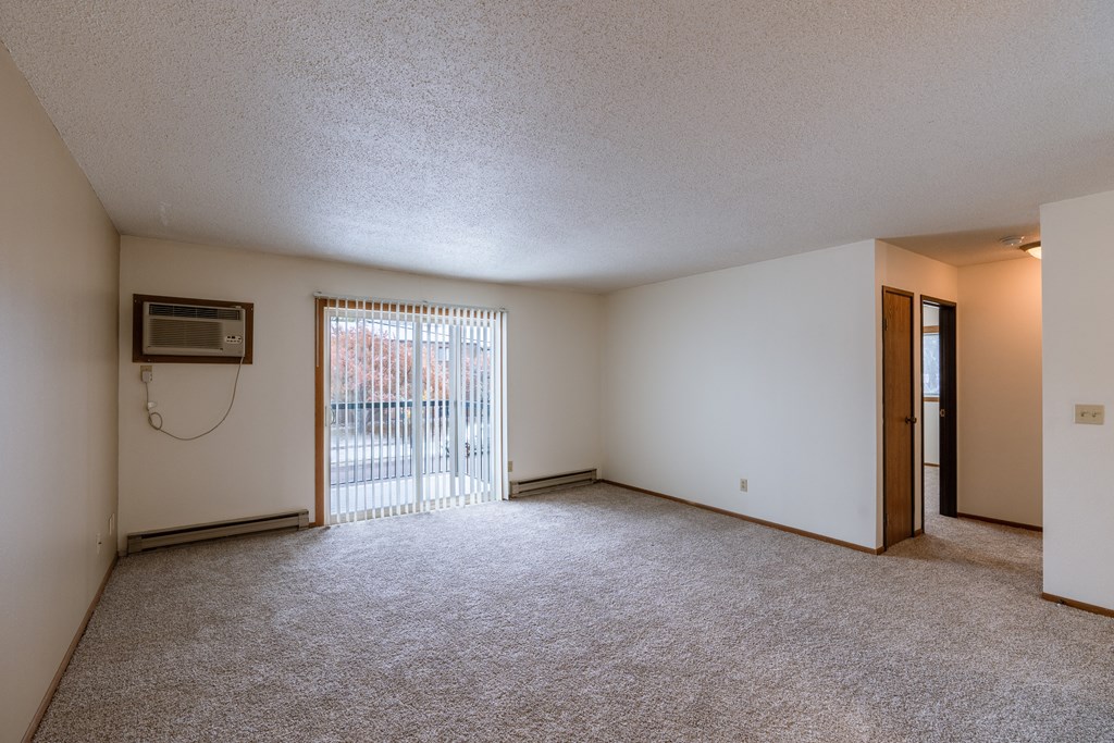 the living room of an apartment with a sliding glass door. Fargo, ND West Oak Apartments.