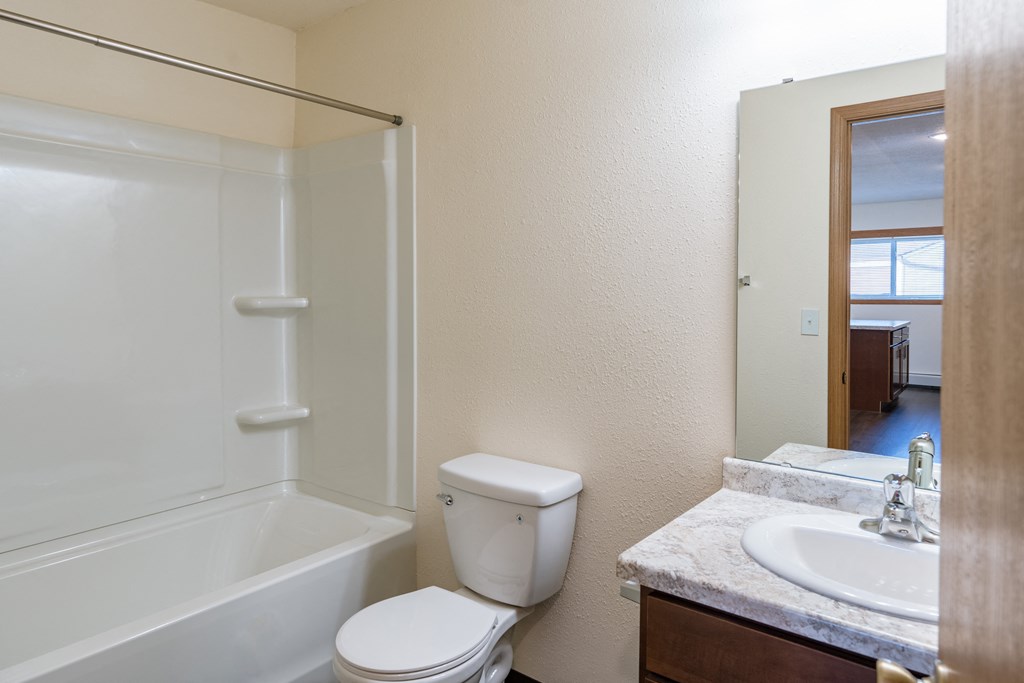a bathroom with a sink and a toilet and a shower. Fargo, ND Westwood Apartments