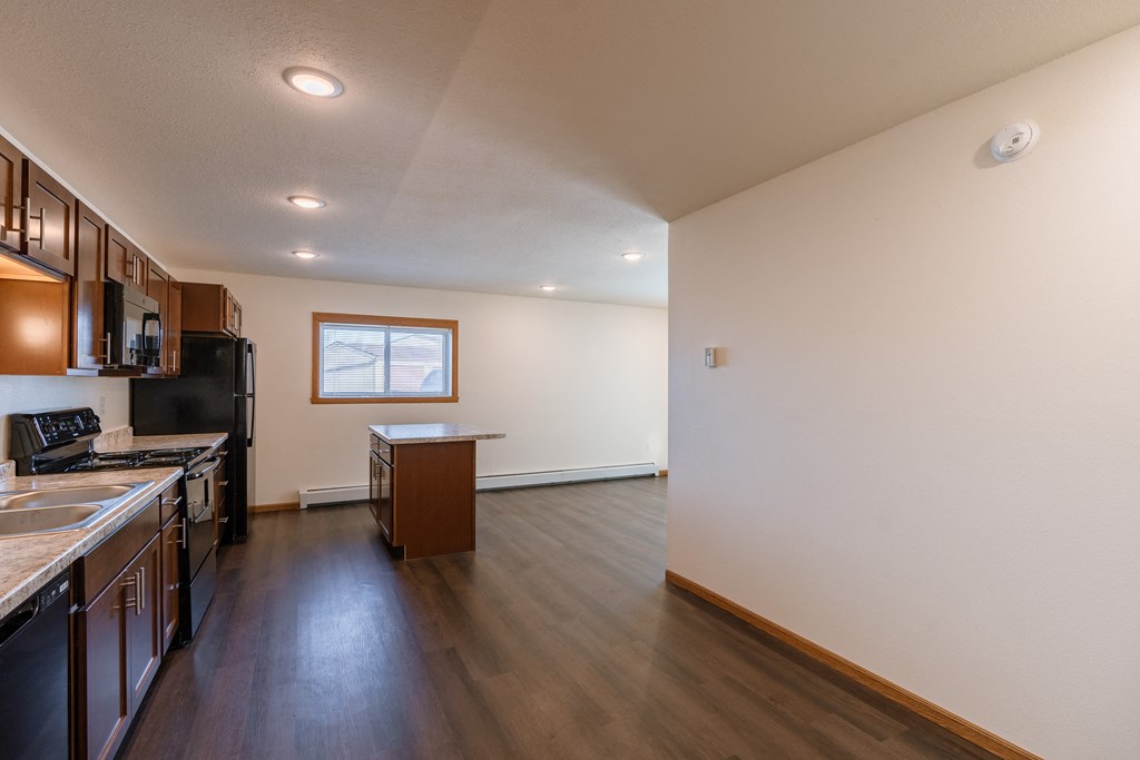 a kitchen with black appliances and a window with a dining room. Fargo, ND Westwood Apartments
