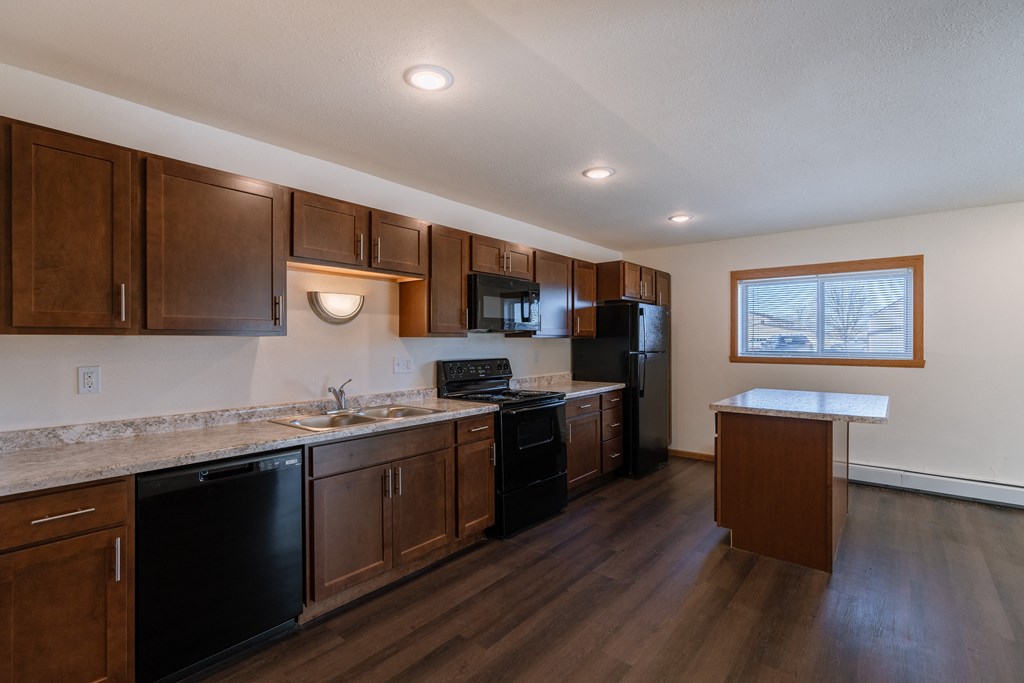 a kitchen with black appliances and white countertops. Fargo, ND Westwood Apartments