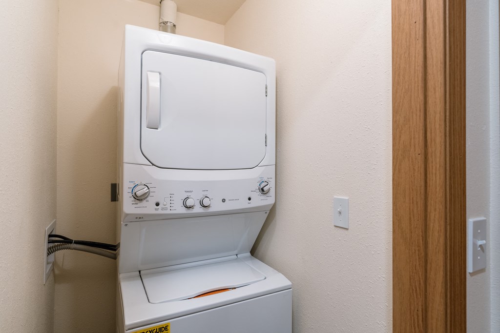 a laundry closet with a washer and dryer on top of each other. Fargo, ND Westwood Apartments