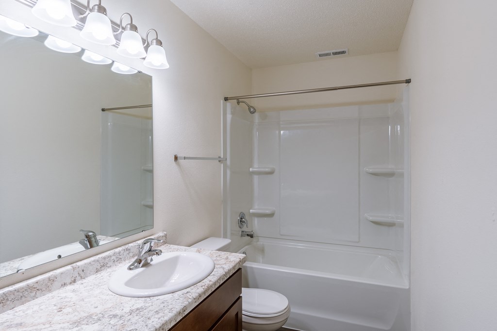 a bathroom with a sink and a toilet and a shower. Fargo, ND Westwood Apartments