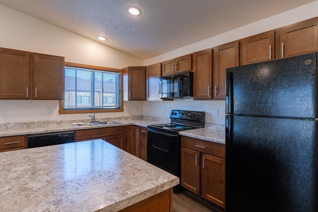 a kitchen with black appliances and white countertops. Fargo, ND Westwood Apartments