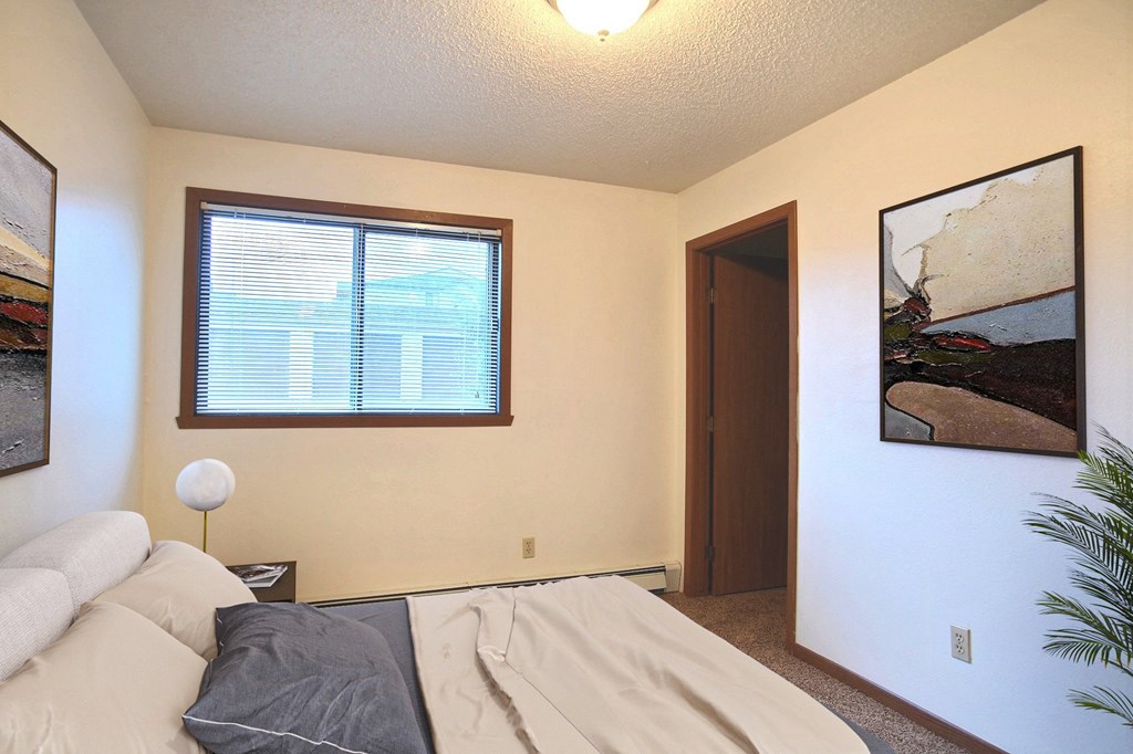 a bedroom with a bed and a window. Fargo, ND Westwood Estates Apartments