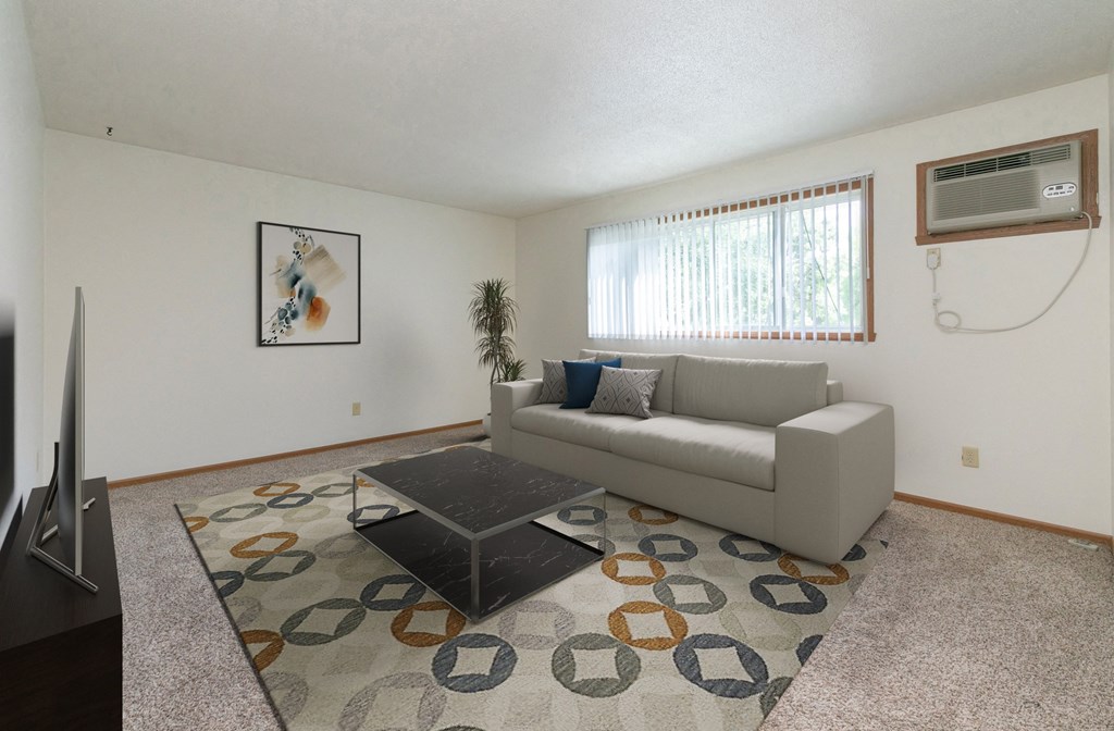a living room with a couch and a coffee table with a window in the back. Fargo, ND White Ridge Apartments