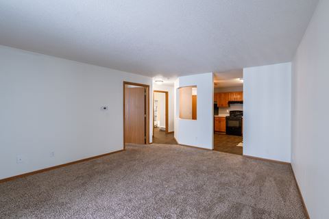 a living room  with a kitchen in the background Fargo, ND Willow Park Apartments.