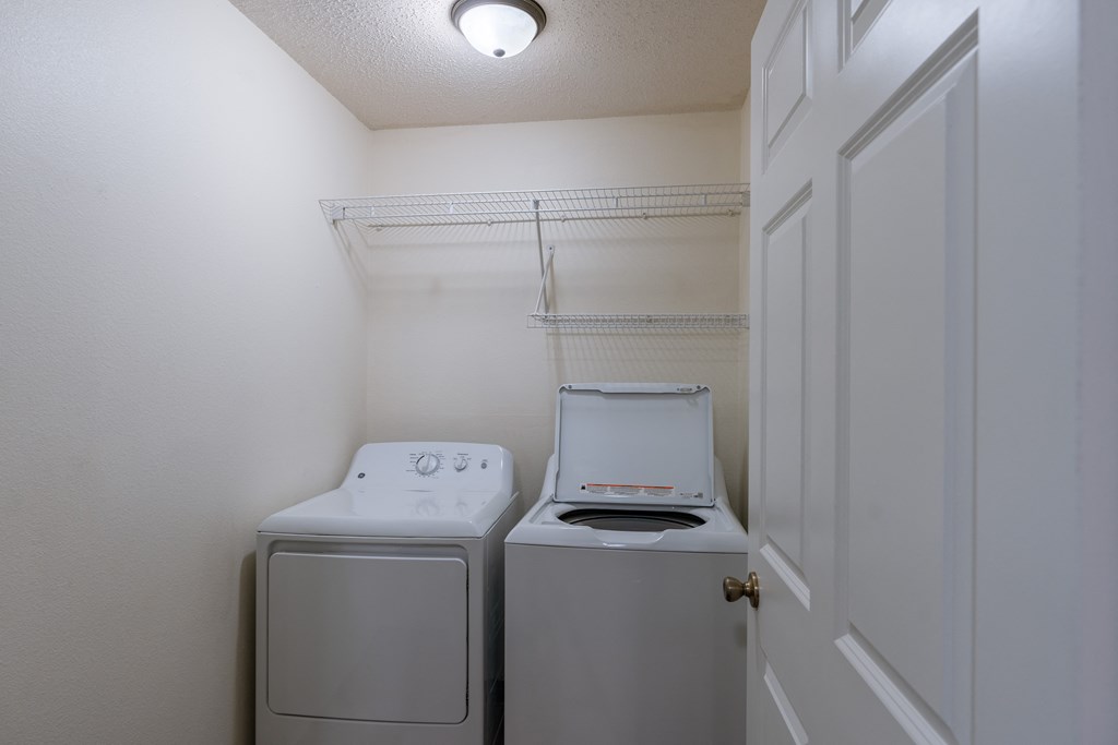 a laundry room with a shelf, washer, and dryer. Fargo, ND Willow Park Apartments