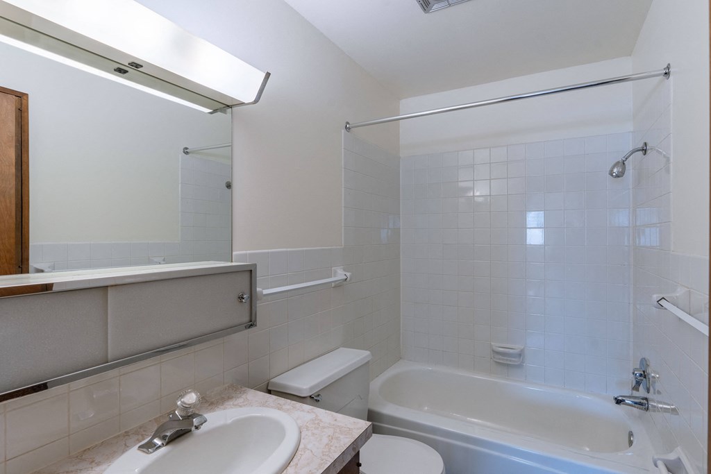 a bathroom with a tub and a sink and a mirror. Fargo, ND Windsor Apartments