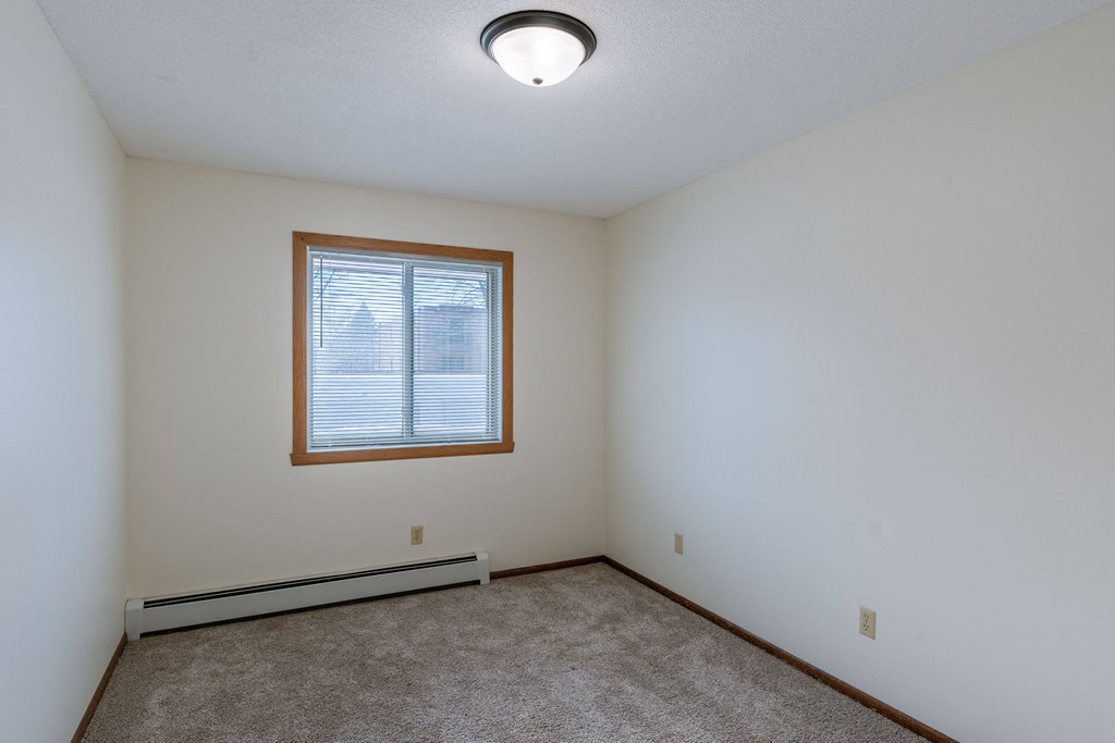the living room with carpet and a window. Fargo, ND Windsor Apartments