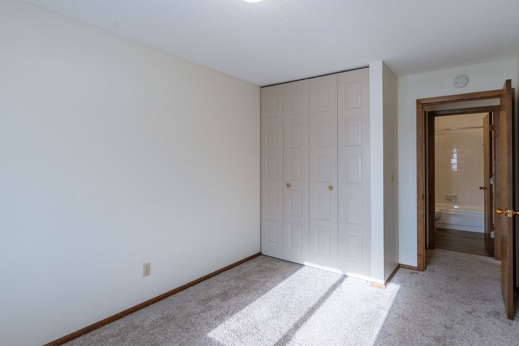 a bedroom with a closet and a door to a bathroom. Fargo, ND Windsor Apartments