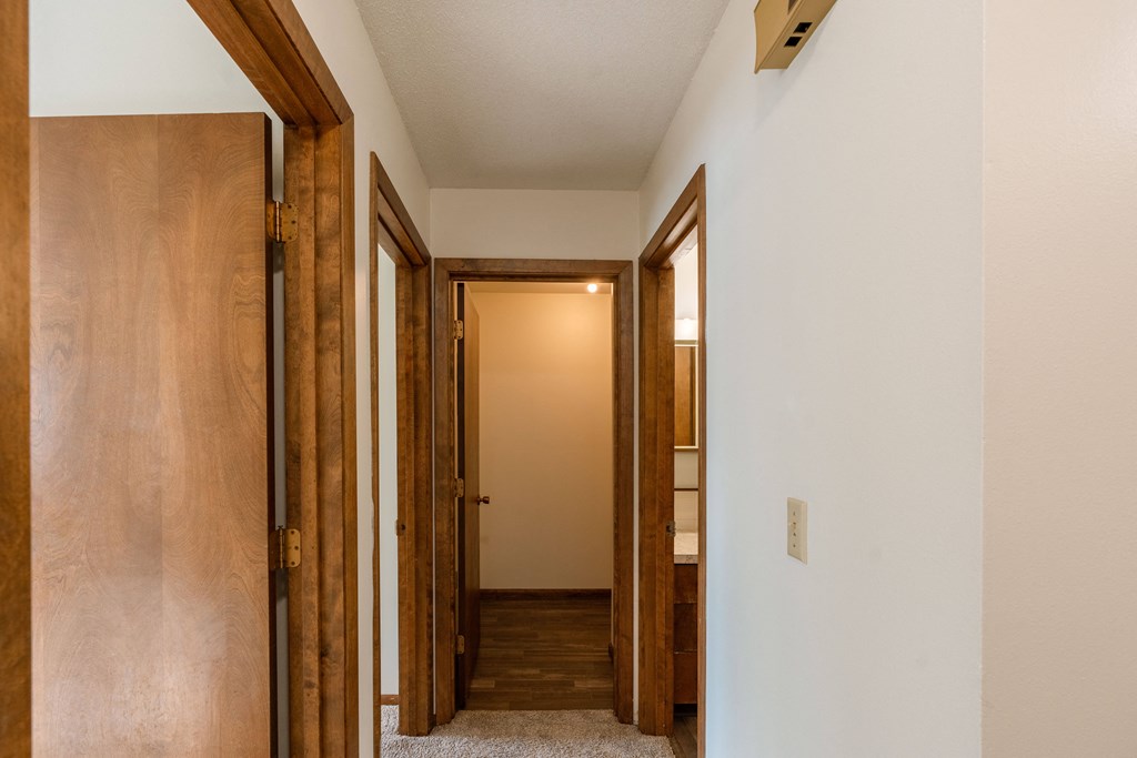 a hallway with wooden doors and a door to a bathroom. Fargo, ND Windsor Apartments