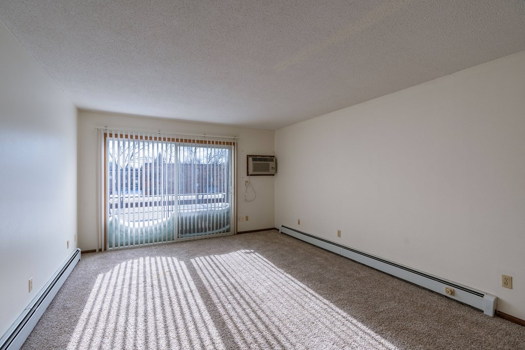 the living room of an apartment with a sliding glass door. Fargo, ND Windsor Apartments