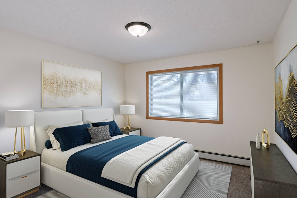 a bedroom with a white bed and a blue and white comforter. Fargo, ND Windsor Apartments