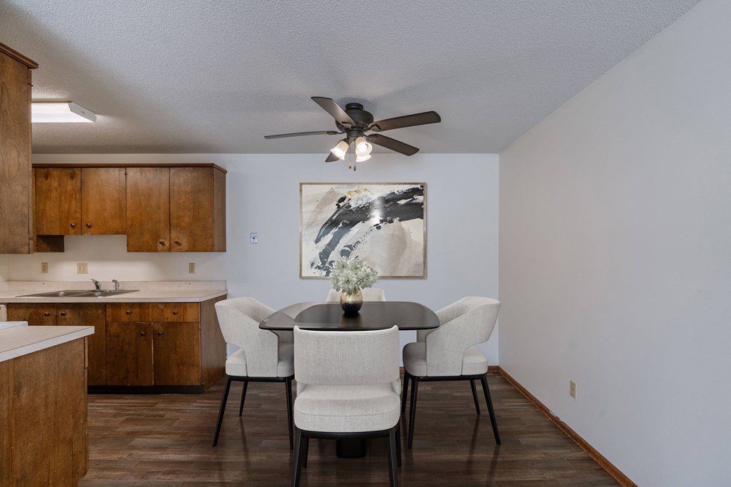a dining room with a table and chairs and a ceiling fan. Fargo, ND Windsor Apartments