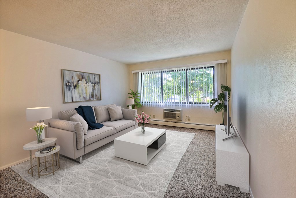 a living room with a couch coffee table and a window. Fargo, ND Woodland Apartments