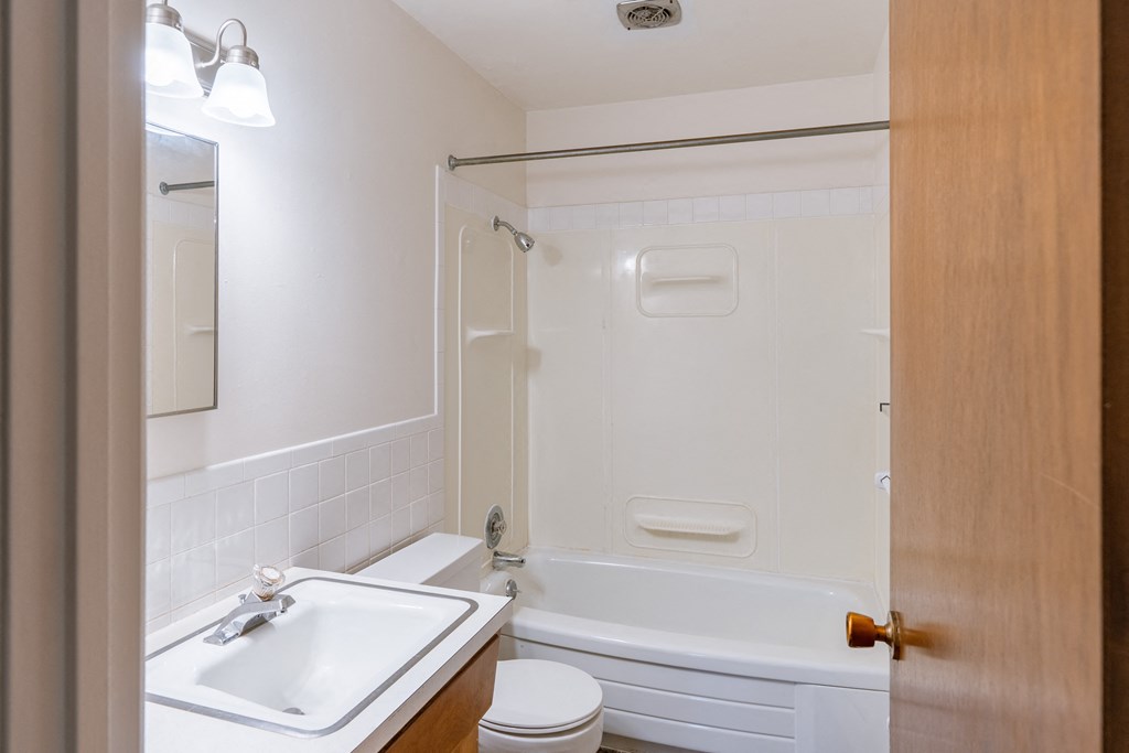 a bathroom with a sink toilet and tub and a mirror. Fargo, ND Woodland Apartments |