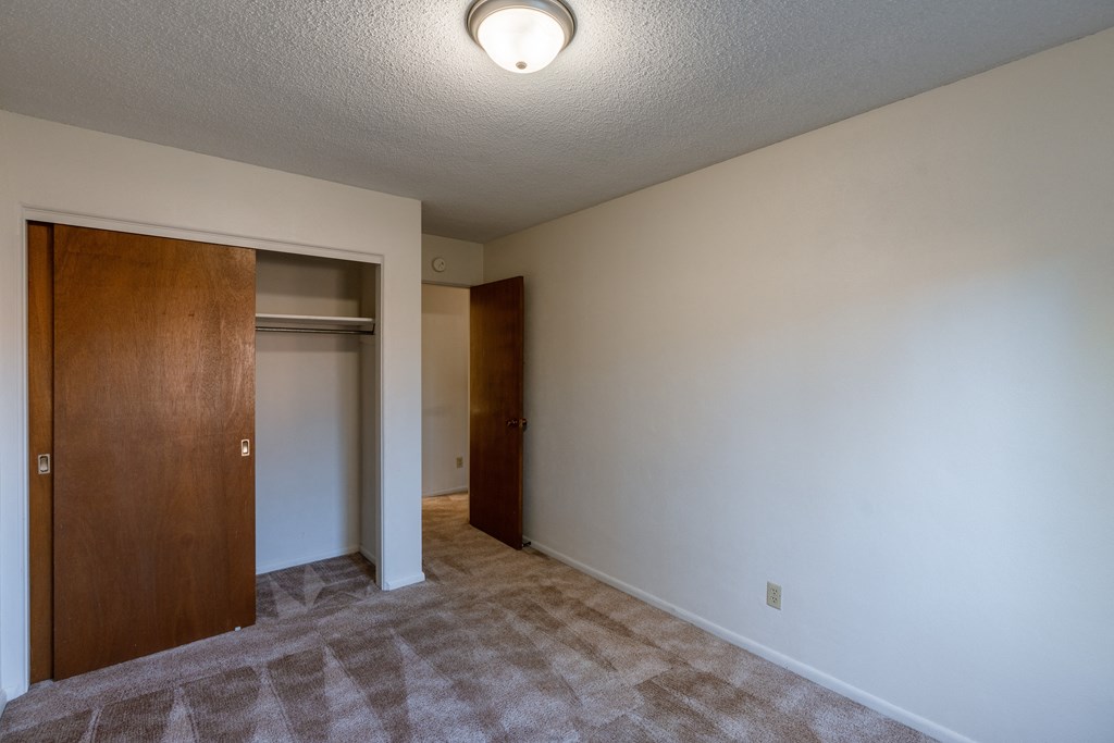 a bedroom with a door to a closet. Fargo, ND Woodland Apartments