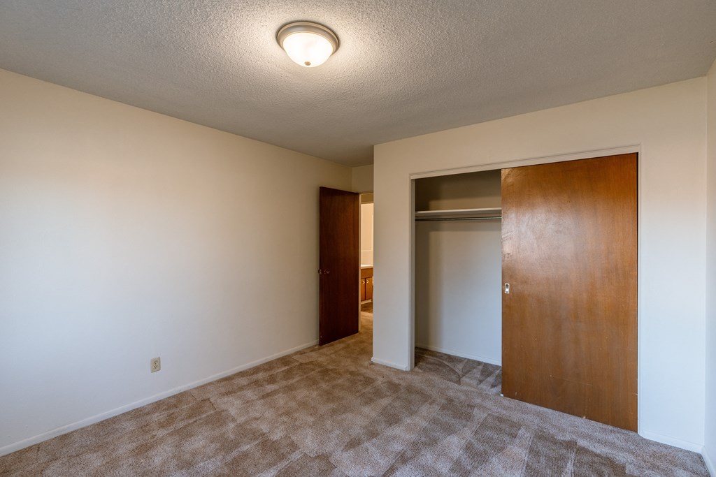 a bedroom with a door to a closet. Fargo, ND Woodland Apartments