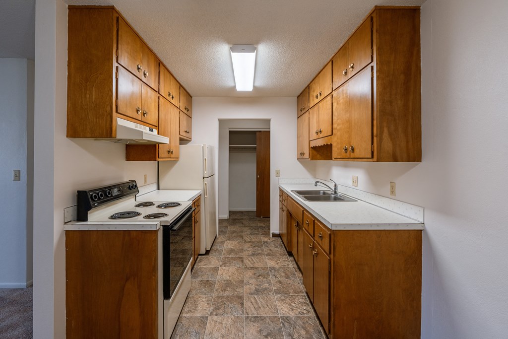 a kitchen with white appliances and wood cabinets. Fargo, ND Woodland Apartments