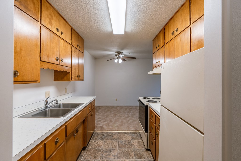 a kitchen with white appliances and wooden cabinets. Fargo, ND Woodland Apartments