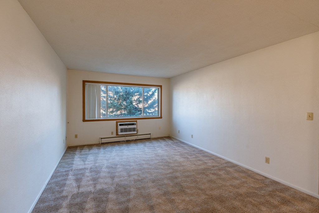 an empty living room with a window in the corner. Fargo, ND Woodland Apartments