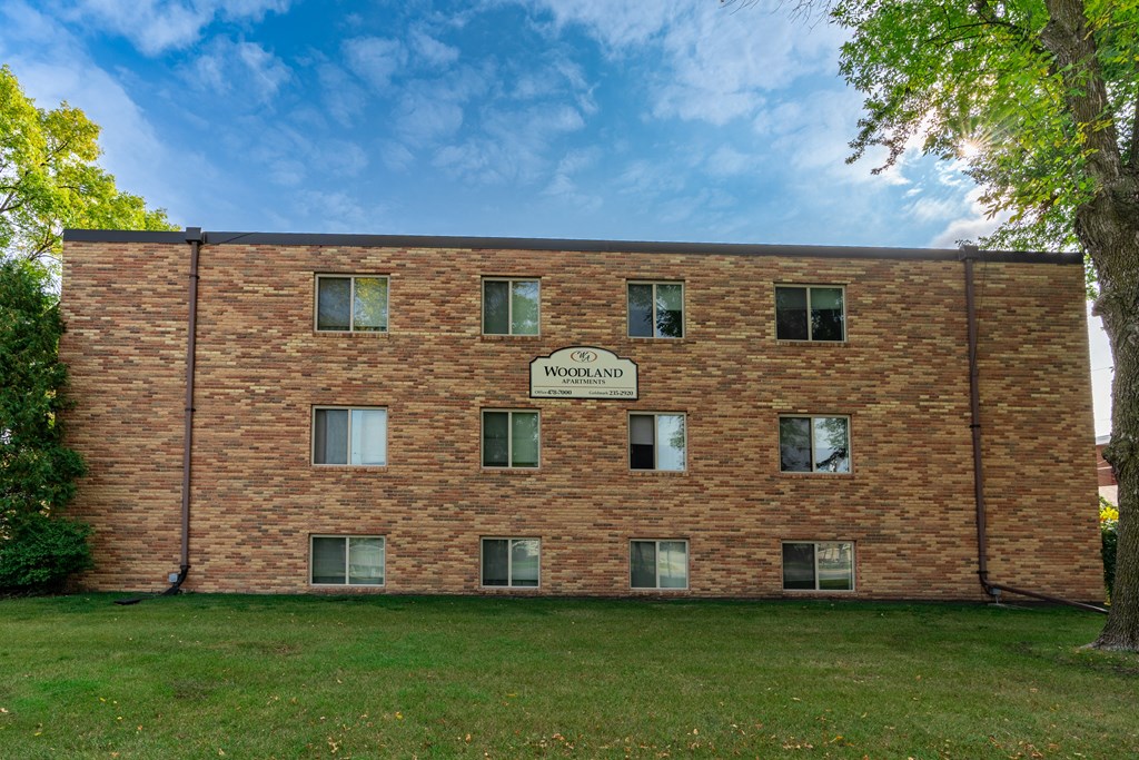 a brick building with a sign on the side of it. Fargo, ND Woodland Apartments