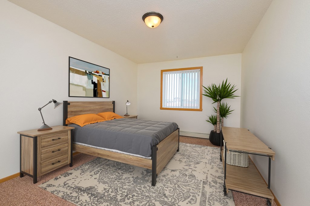 a bedroom with a bed and a desk and a window. Moorhead, MN Woodstone Apartments