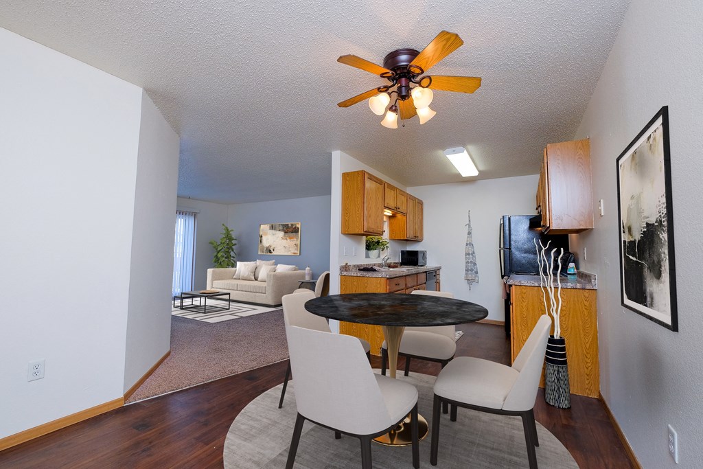 a living room and dining room with a kitchen and a ceiling fan. Moorhead, MN Woodstone Apartments