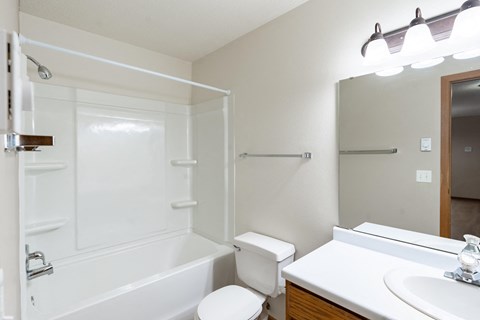 a bathroom with a shower toilet and sink and a mirror. Fargo, ND Briar Pointe Apartments