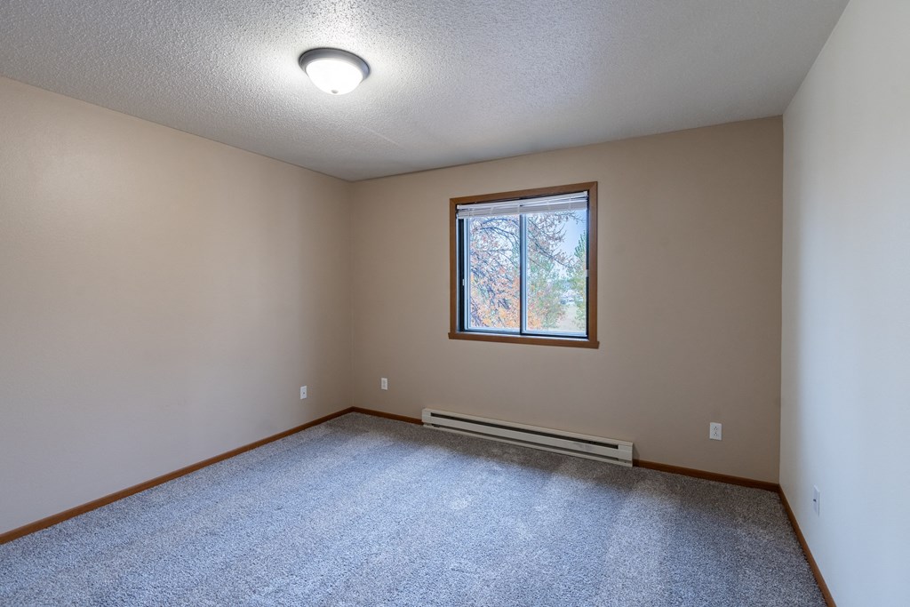 a bedroom with a window and carpet. Fargo, ND Briar Pointe Apartments